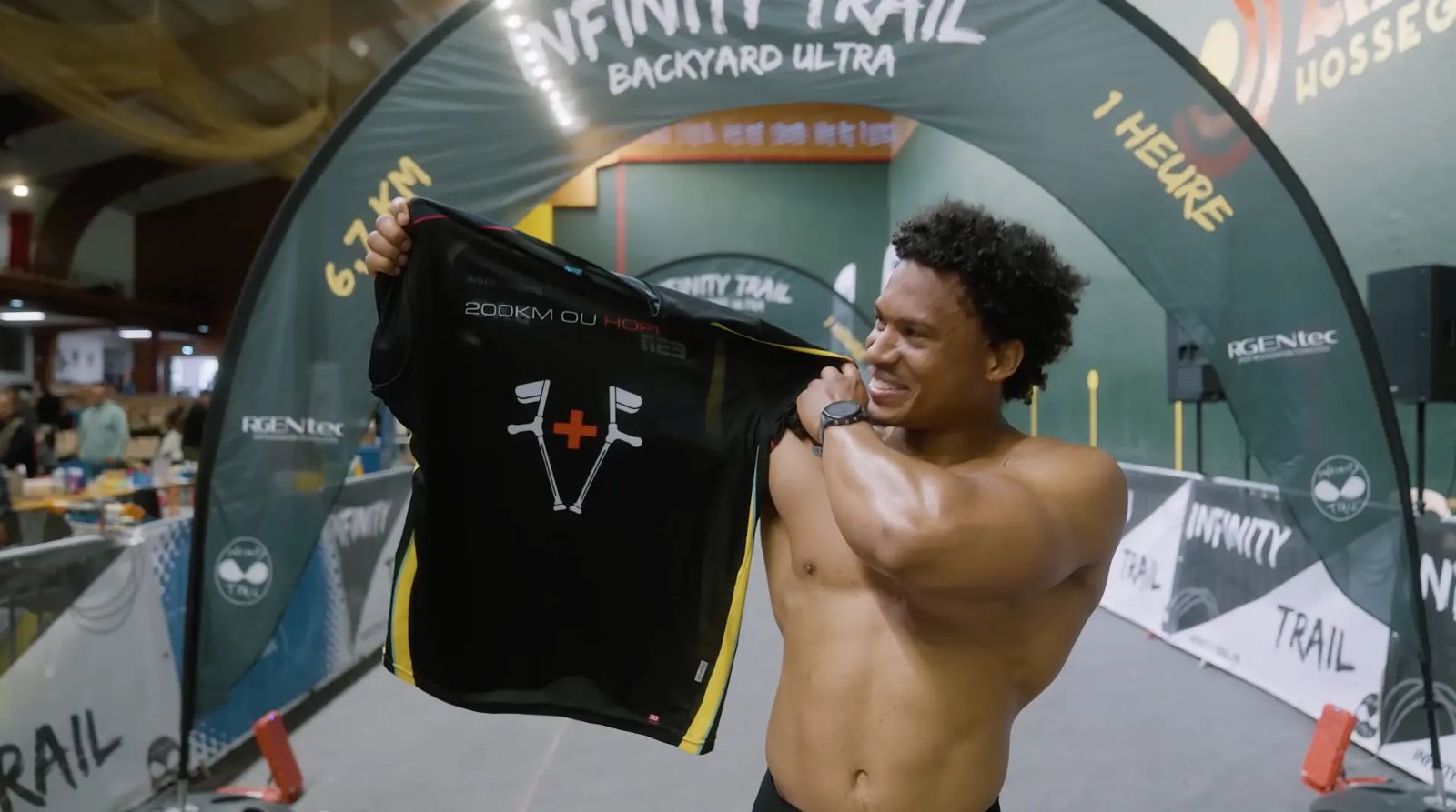 Joey Blanc présentant son maillot 200 km ou hôpital sous l'arche Infinity Trail