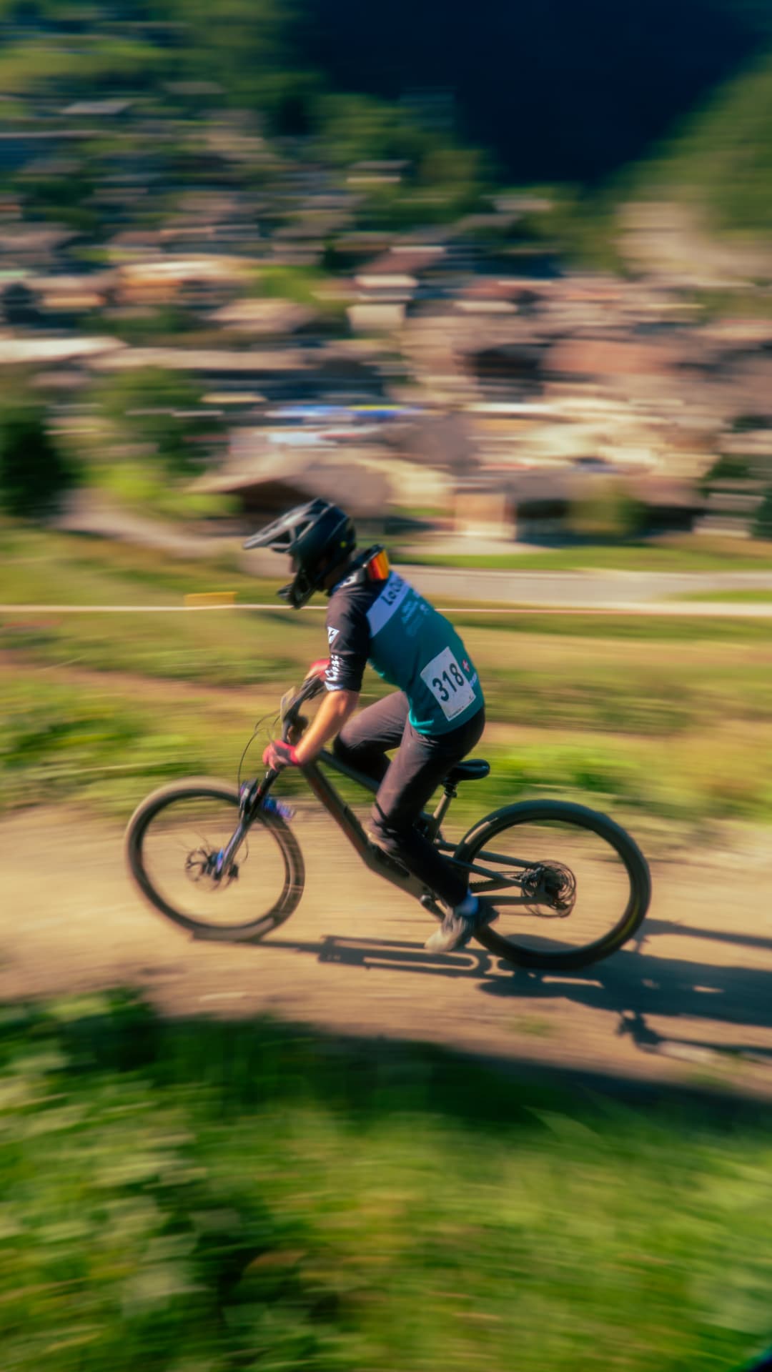 Photographe VTT Annecy — pilote en descente, filé au-dessus du village