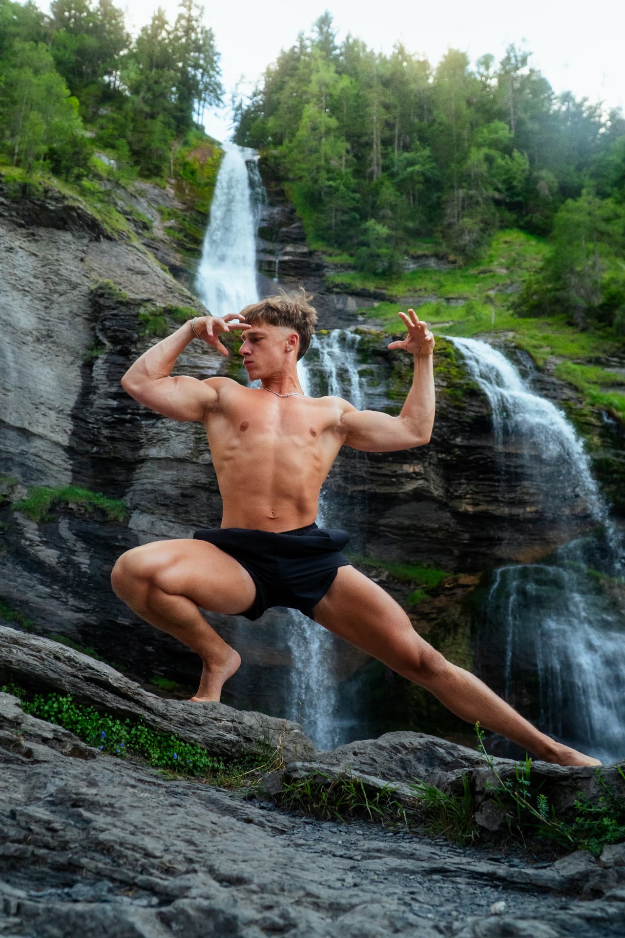 William, créateur de contenu fitness, pose devant une cascade en montagne